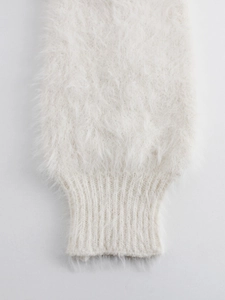 Macro shot of fluffy long plush knit texture with ribbed cuffs on white cardigan