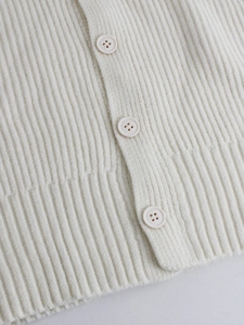 Close-up of cream white ribbed knit vest showing textured fabric and three buttons