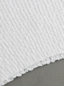 Detalle de tejido de punto blanco con diseño calado y textura de rayas verticales