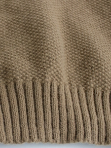 Detailed macro view of camel knit sweater texture featuring moss stitch and ribbed hem