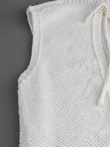Close-up of cream crochet knit sleeveless top showing detailed texture and ribbed neckline
