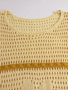 Close-up of knit hollow-out vest with mustard yellow stripe and crochet texture
