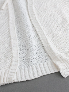 Close-up of cream white knitted sweater with premium ribbed hem and soft wool texture