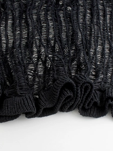 Detail of distressed knit texture and ribbed hem on a black hollow out beach dress