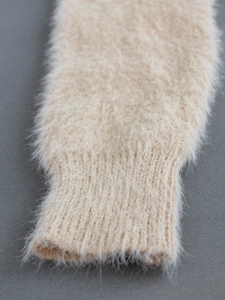Détail de la manche d'un cardigan beige en maille douce avec texture pelucheuse et bords