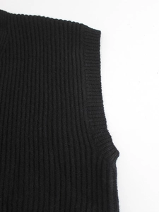 Detail of a black V-neck ribbed knit vest showing high-quality stitching at the armhole