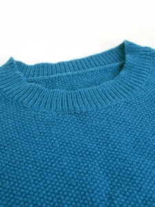 Detail of round neckline and rib-knit texture on a peacock blue long sleeve sweater