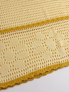 Detail of crochet knit fabric with beige and gold stripes and scalloped pointelle hem
