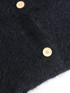 Close-up of black fuzzy knit cardigan featuring plush texture and beige round buttons