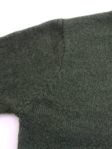 Close-up of dark green knitted sweater showing premium rib texture and wool blend fabric