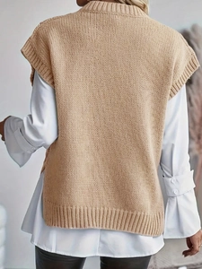 Back view of women's cable knit camel vest layered over a white shirt and black trousers