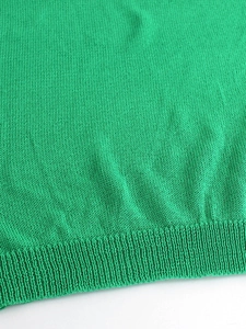 Dettaglio di un maglione verde a maglia con scollo a V e polsini a coste rifiniti