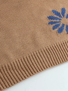 Beige knit pullover sweater featuring blue sunflower jacquard patterns and ribbed hem detail
