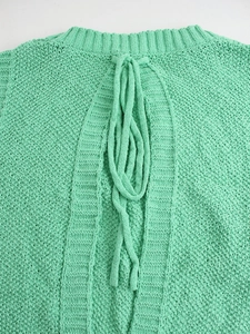 Detail of mint green knit top featuring a backless design with thick lace-up ties