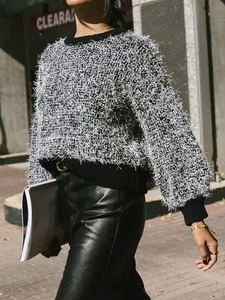 Detailed close-up of fringe texture on grey and white knit sweater with black ribbed cuffs