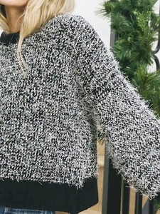 Detail of soft feather yarn knit sweater with contrast black ribbed crew neck and hem
