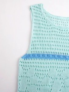 Detail of mint green crochet knit vest featuring hollow mesh texture and blue twisted cable trim