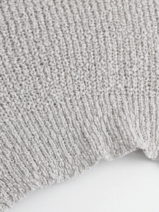 Detalle macro de punto bouclé gris con textura de dobladillo acanalado en el suéter