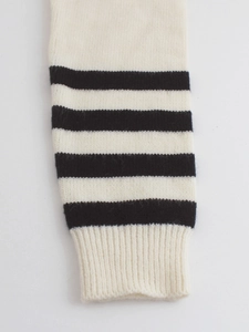 Detailed macro view of the striped knit sweater featuring elastic ribbed cuffs and soft texture