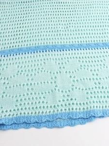 Detail of knit hollow mesh fabric with blue stripes and scalloped wavy edges