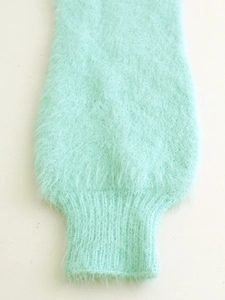 Detail of light green fuzzy knit cardigan showing soft texture and ribbed cuff finishing