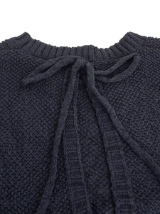 Detail of navy knit top featuring textured popcorn fabric and elegant neck tie bow