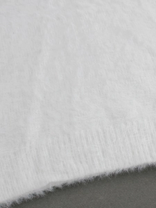 Gros plan sur la maille mohair blanche montrant la texture douce et l'ourlet côtelé