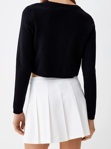 Vue arrière d'un élégant cardigan en tricot noir et d'une mini-jupe plissée blanche