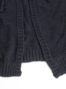 Detailed close-up of dark blue knit fabric showing coarse texture and ribbed hem