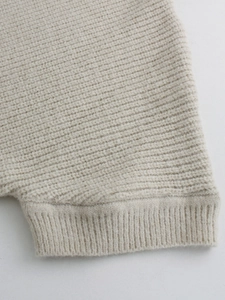 Dettaglio del polsino a coste e della trama in maglia del cardigan color beige