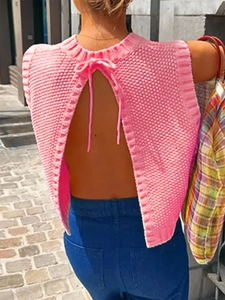 Detail of pink knitted backless vest featuring textured fabric and a neck tie-back design