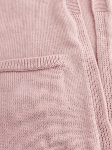 Close-up detail of soft pink knit cardigan showing ribbed pocket texture and fine fabric