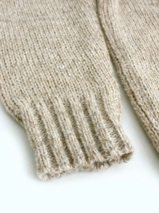 Detail of ribbed cuff on beige chunky knit sweater with warm textured wool feel