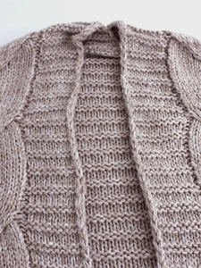 Flat lay of oatmeal knit cardigan sweater with thick cable knit texture and open front