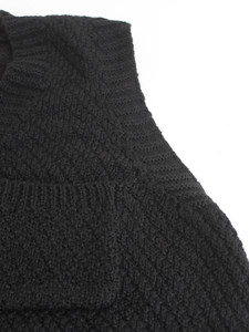 Close-up of black knit vest shoulder seam showing detailed textured stitching