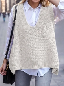 Detail of cream V-neck knitted vest with chest pocket shown on a male model in a city