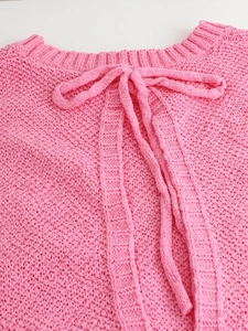 Detailed view of pink chunky knit sweater with round neckline and bow tie design
