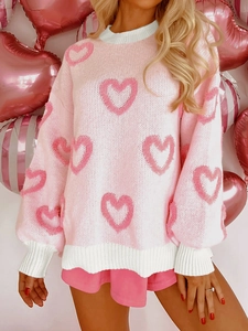 Detail of loose knit sweater showing textured pink hearts and white ribbed edges