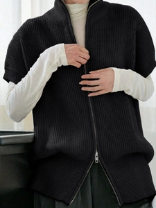 Texture dettagliata del gilet in maglia nera a costine con collo alto e cerniera in metallo