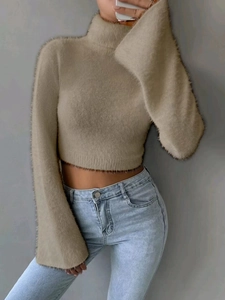 Detailed close-up of fuzzy beige turtleneck cropped sweater with plush knit texture