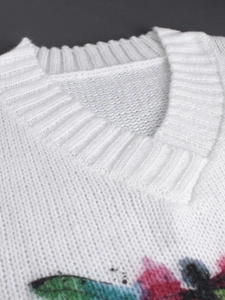 Detailed view of white V-neck sweater showing fine knit texture and colorful patterns