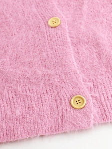 Macro view of pink long-hair knit cardigan with textured fabric and wooden buttons
