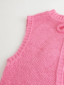 Detail of pink knitted backless vest featuring thick moss stitch texture and ribbed trim