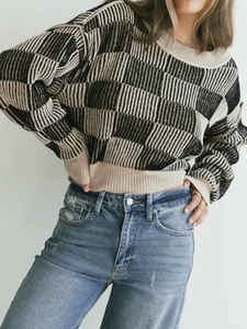 Detail of checkered knit sweater with ribbed cuffs and casual blue denim jeans