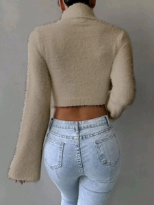 Detail of khaki faux mink fur cropped turtleneck sweater and light blue jeans on model