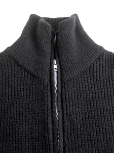 Dettaglio di un cardigan nero a coste con colletto rialzato e cerniera in metallo argento