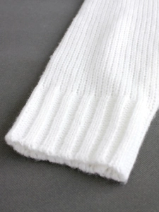 Close-up of the ribbed cuff detail on a white V-neck long sleeve knit sweater