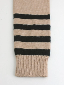 Detailed macro view of camel knit sweater sleeve with black stripes and ribbed cuff
