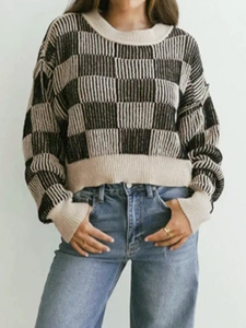 Women's crewneck knit sweater with black and white checkerboard pattern and long sleeves