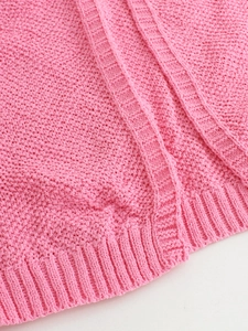 Detail view of pink knit sweater showing chunky texture and ribbed hem craftsmanship